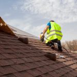Roofer inspecting a pitched tiled roof – roof defects identified during a building survey